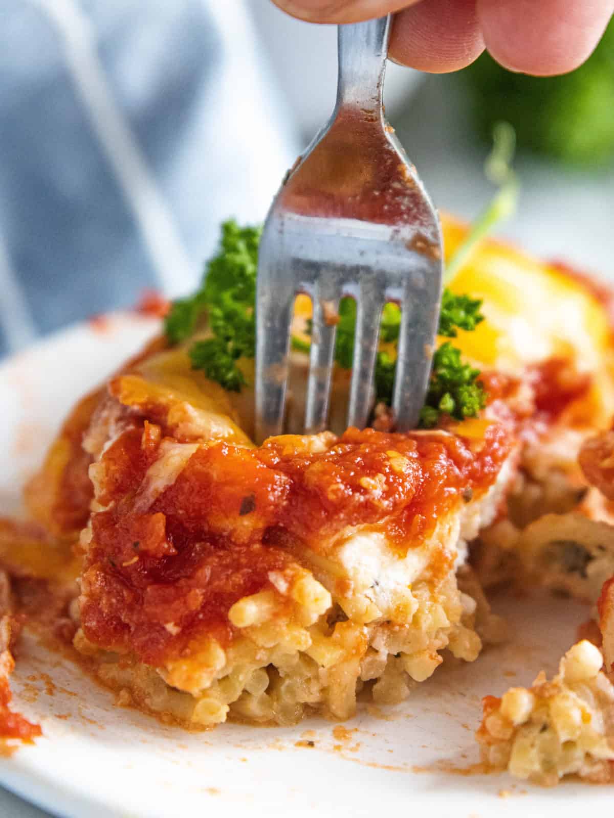 A fork being shown in a piece of baked spaghetti. 