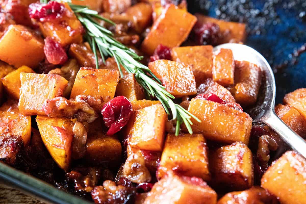 Roasted Butternut Squash with Cranberries and Walnuts being shown in a baking dish. 