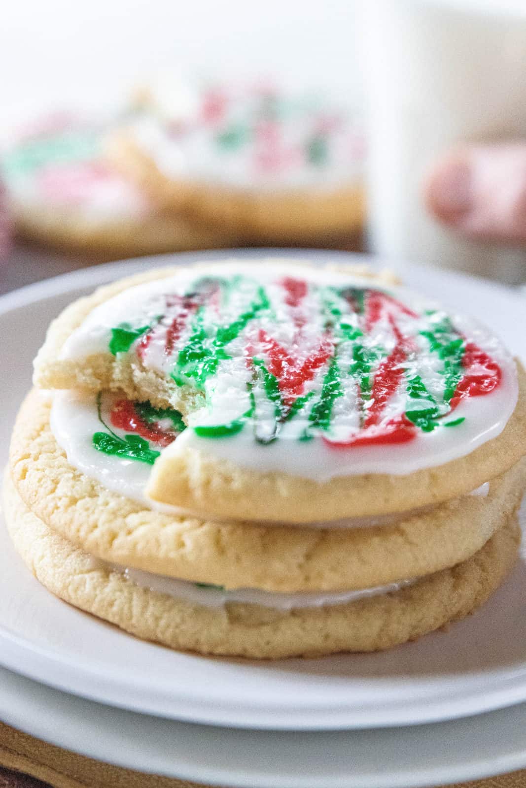 A stack of frosted Christmas cookies being shown on a white plate. 