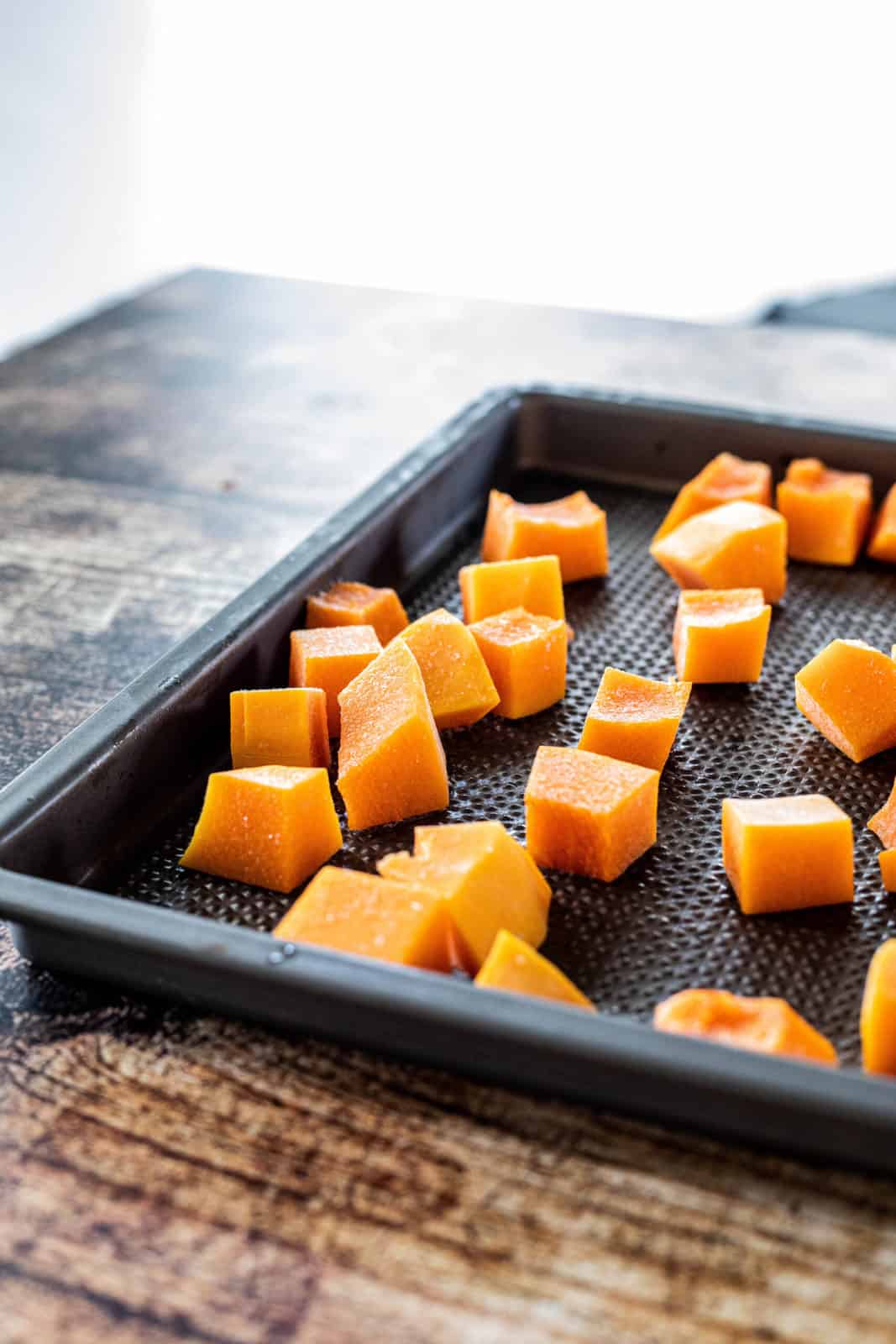 Cut butternut squash on top of a baking sheet. 