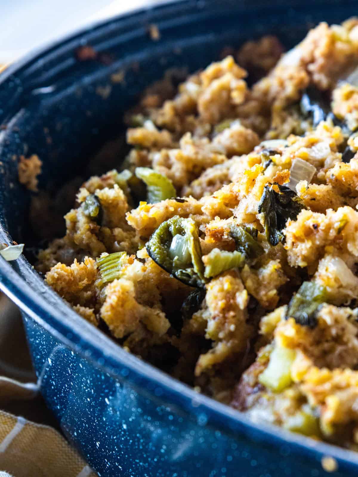 A blue roasting pan being shown filled with homemade stuffing. 