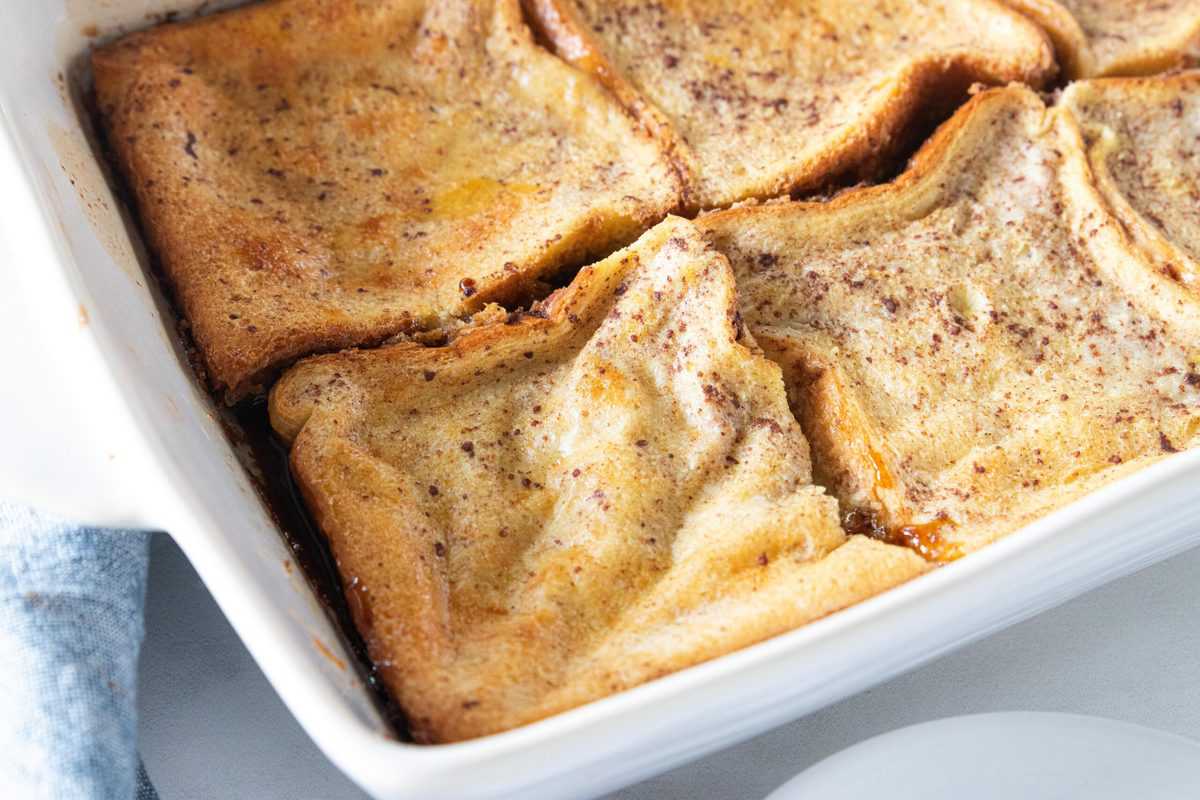 French toast casserole being shown in a white baking dish. 
