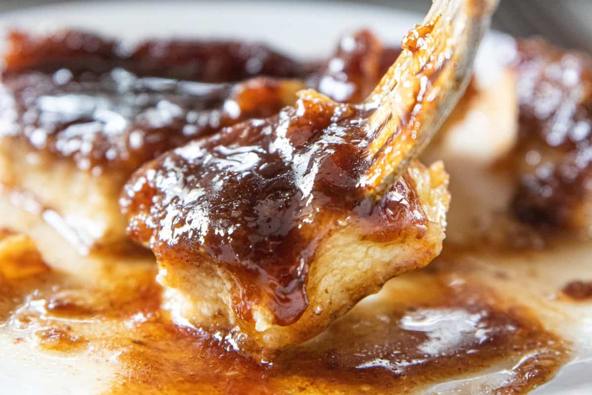 A fork scooping up a bite of French toast casserole from a plate. 