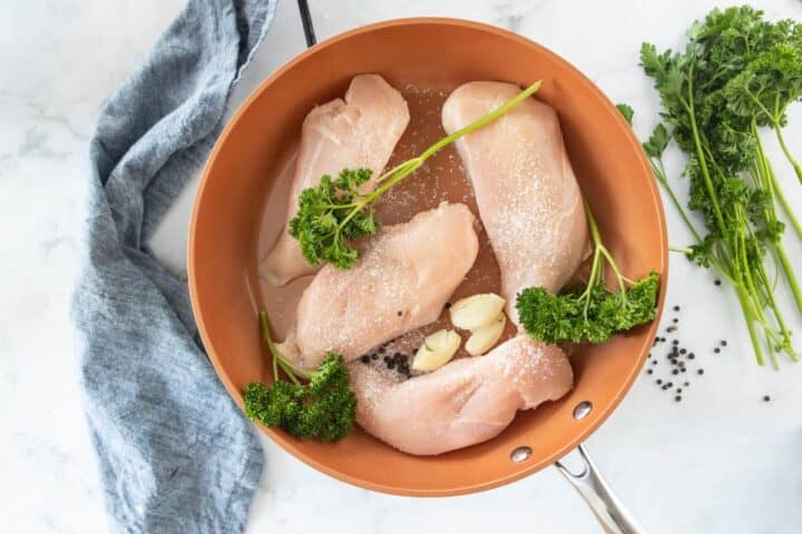 chicken breasts in a skillets seasoned with herbs and salt