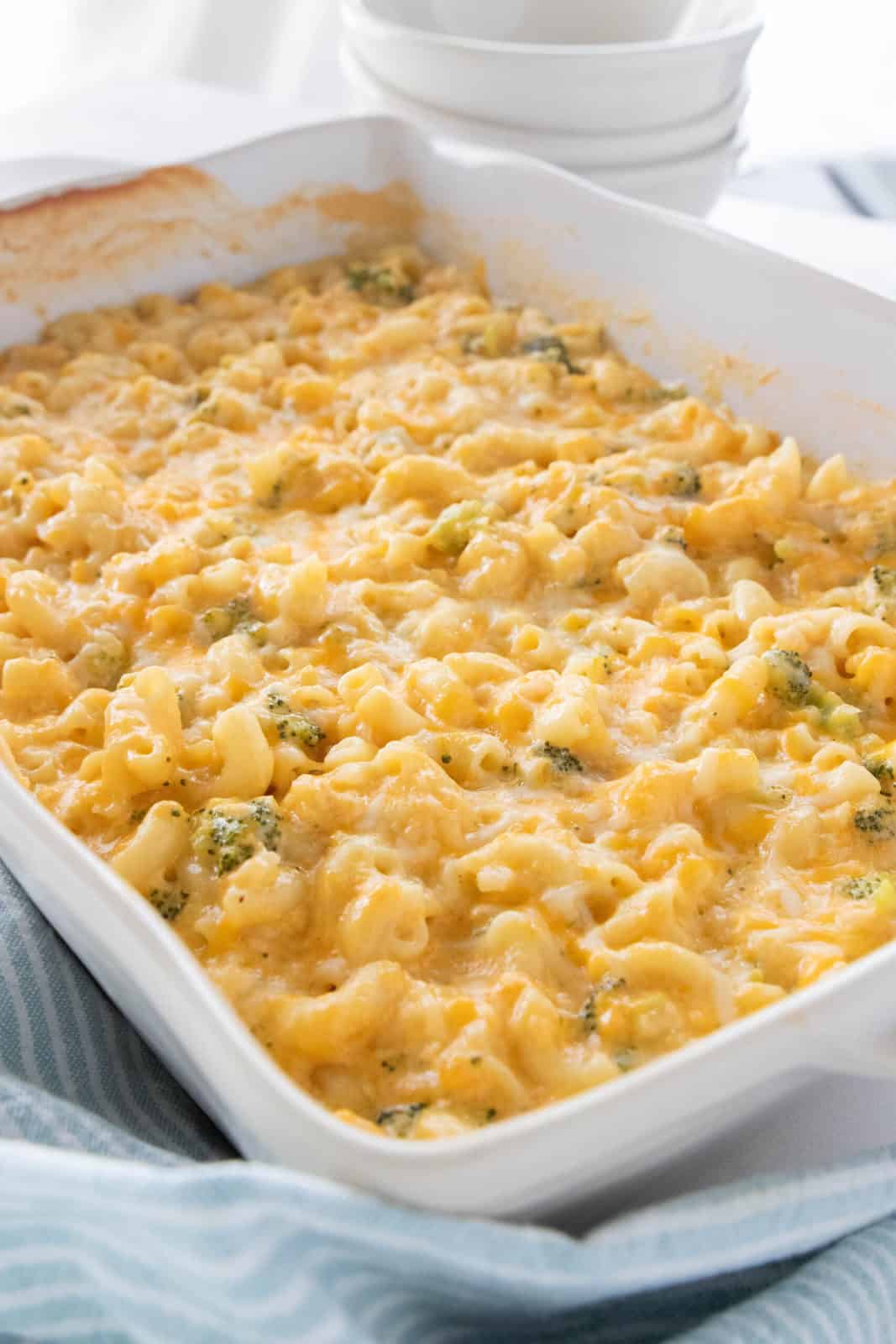 A white baking dish being shown filled with baked veggie Mac and cheese
