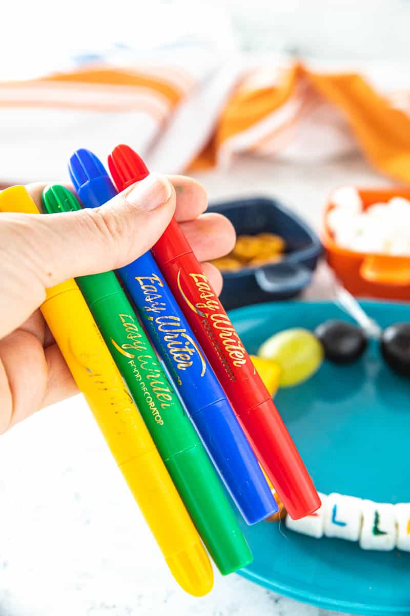 A hand holding 4 edible markers. 