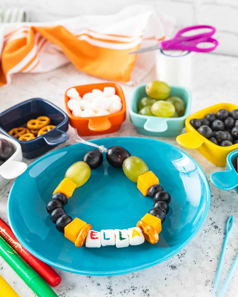 A snack necklace on a plate with various ingredients surrounding the plate. 