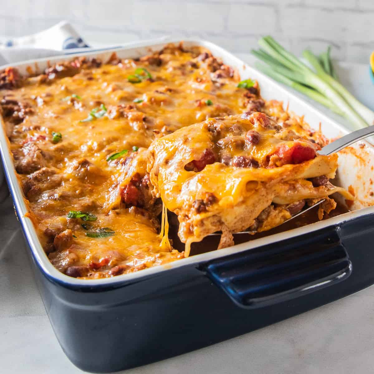 Chili lasagna being scooped from a baking dish. 