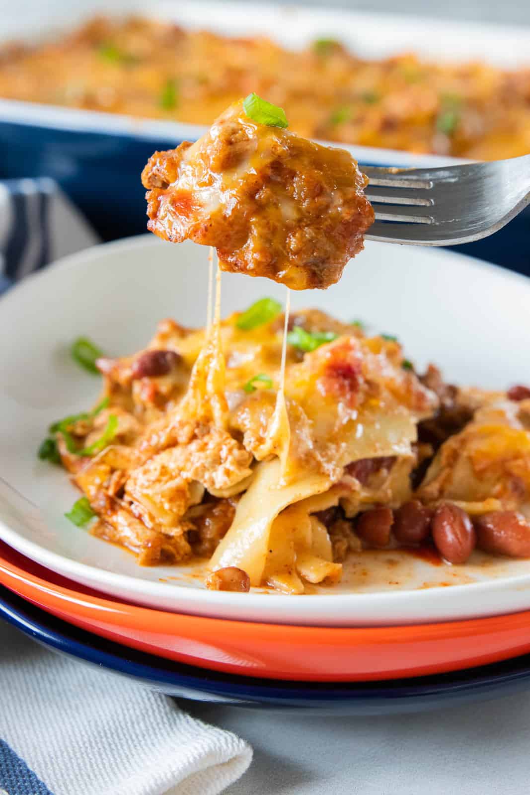 chili lasagna sliced on a plate with a fork taking a bite