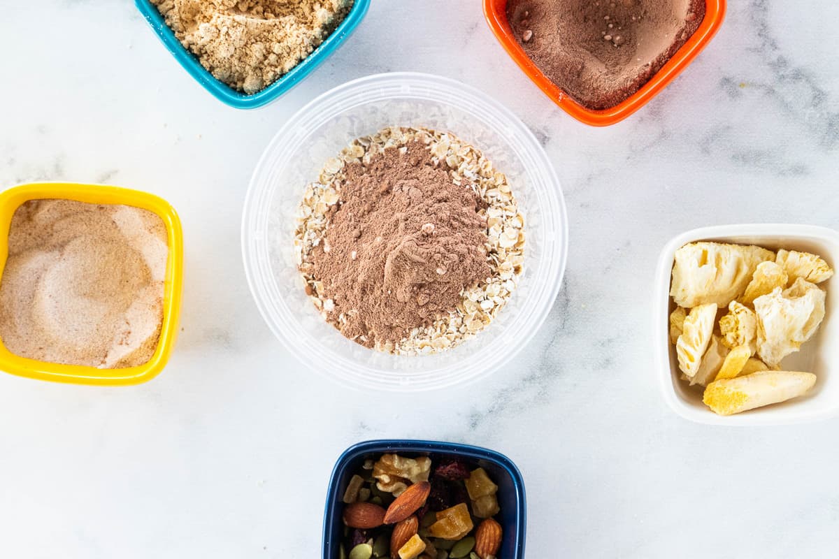 A container of chocolate oats surrounded by a variety of toppings 