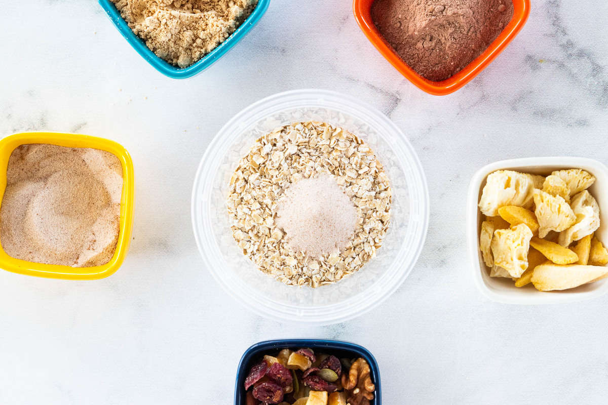 A container of oats surrounded by a variety of toppings 