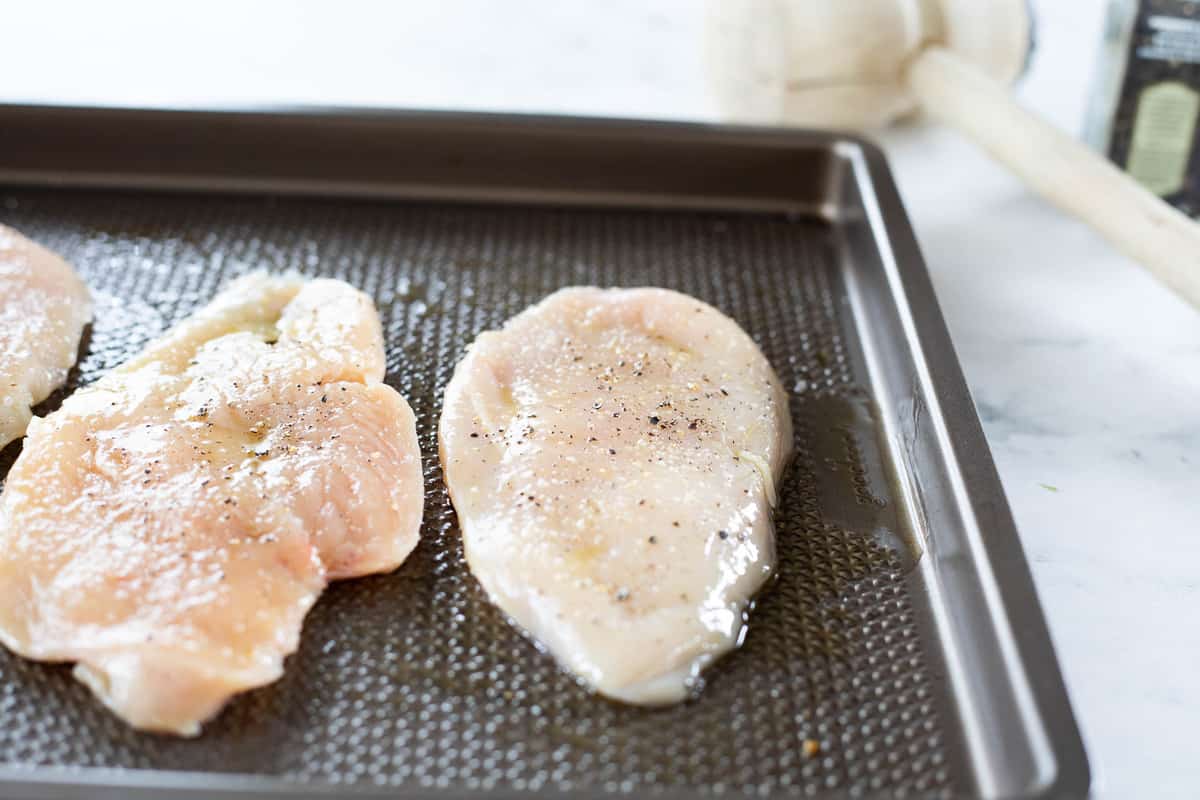 Raw thin sliced chicken breast on a baking tray. 