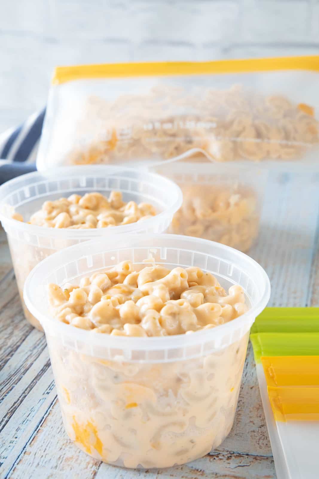 Mac & cheese being shown in plastic containers that are on top of a countertop.