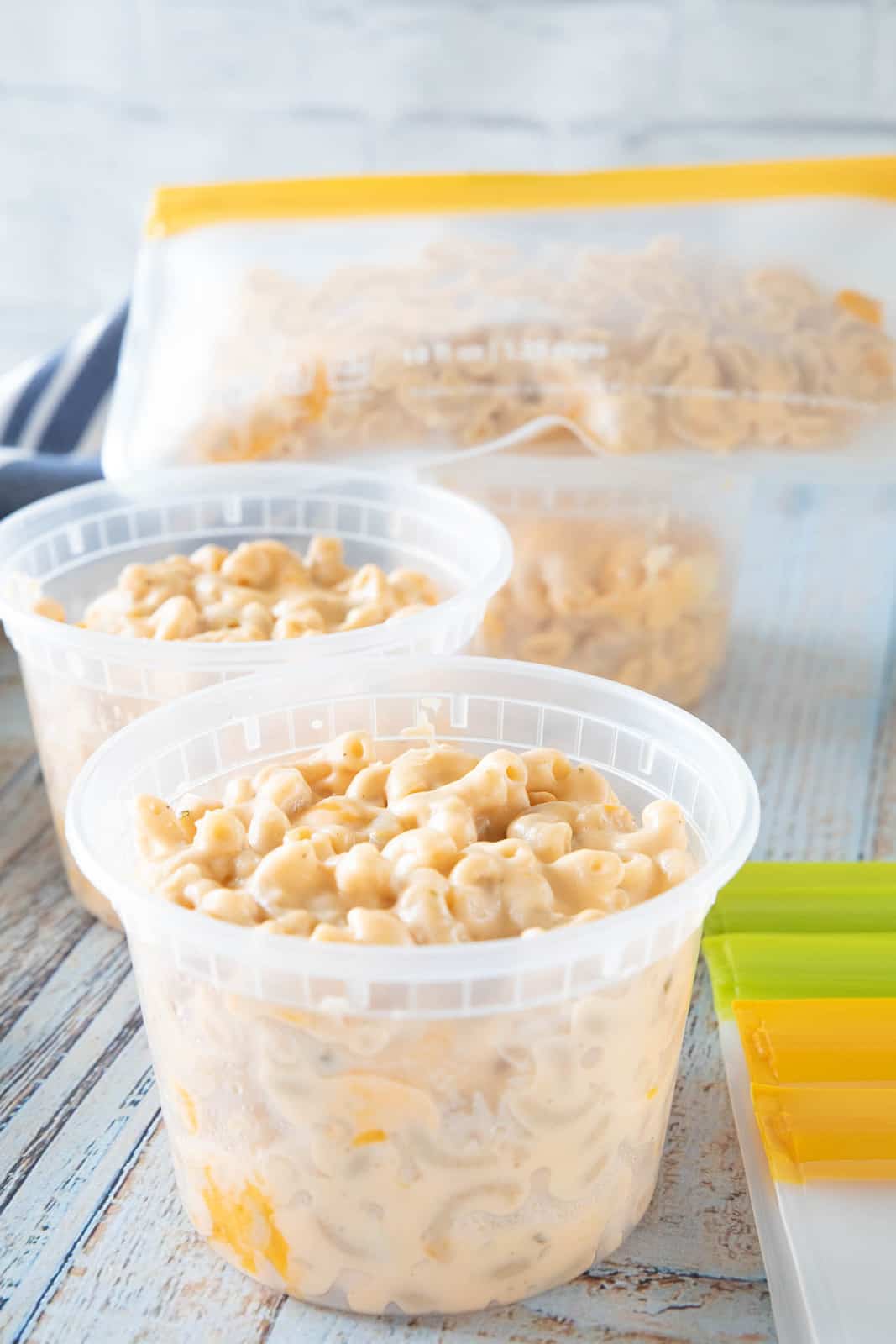 Mac & cheese being shown in plastic containers that are on top of a countertop. 