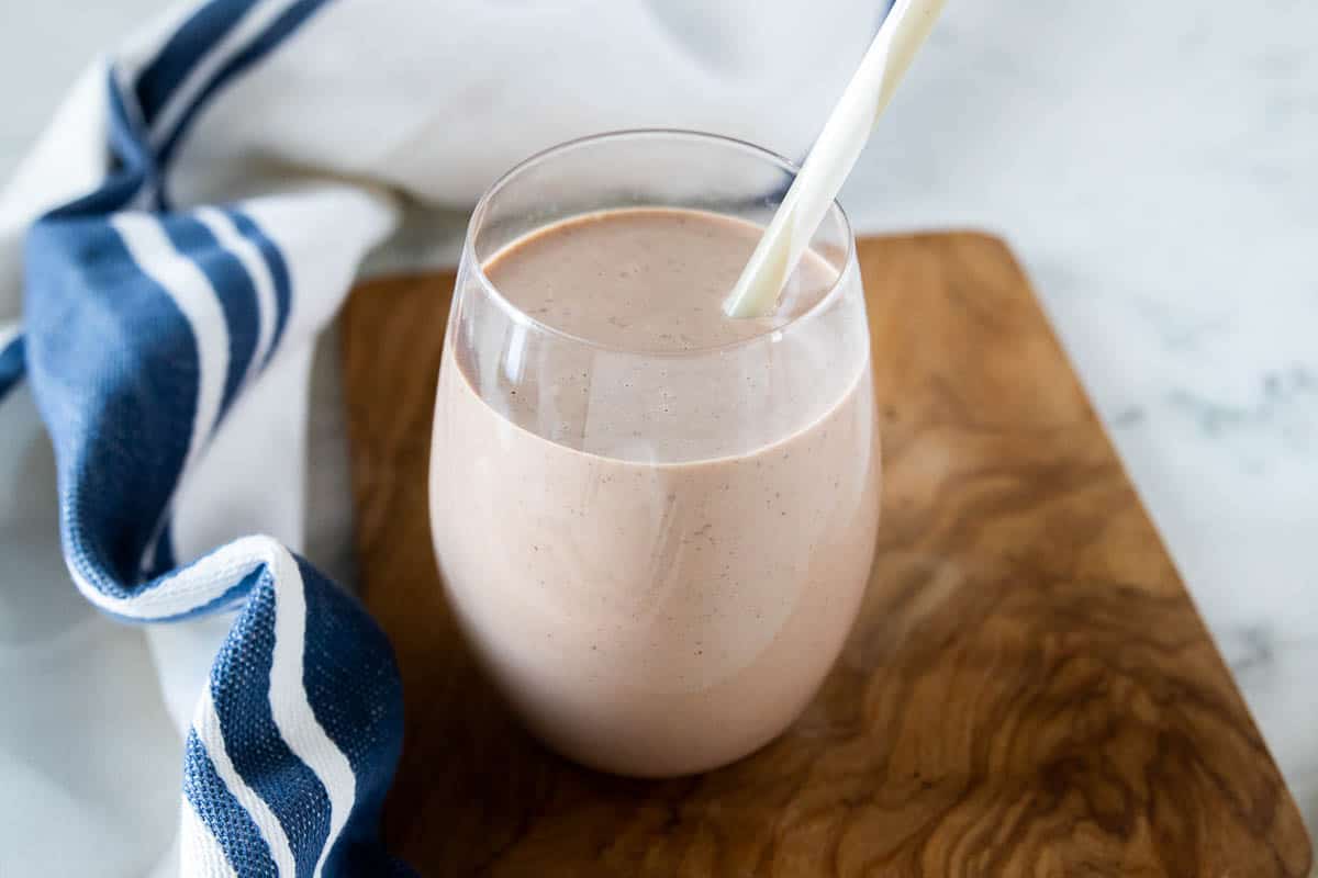 Kids protein shake being shown in a drinking glass with a straw.