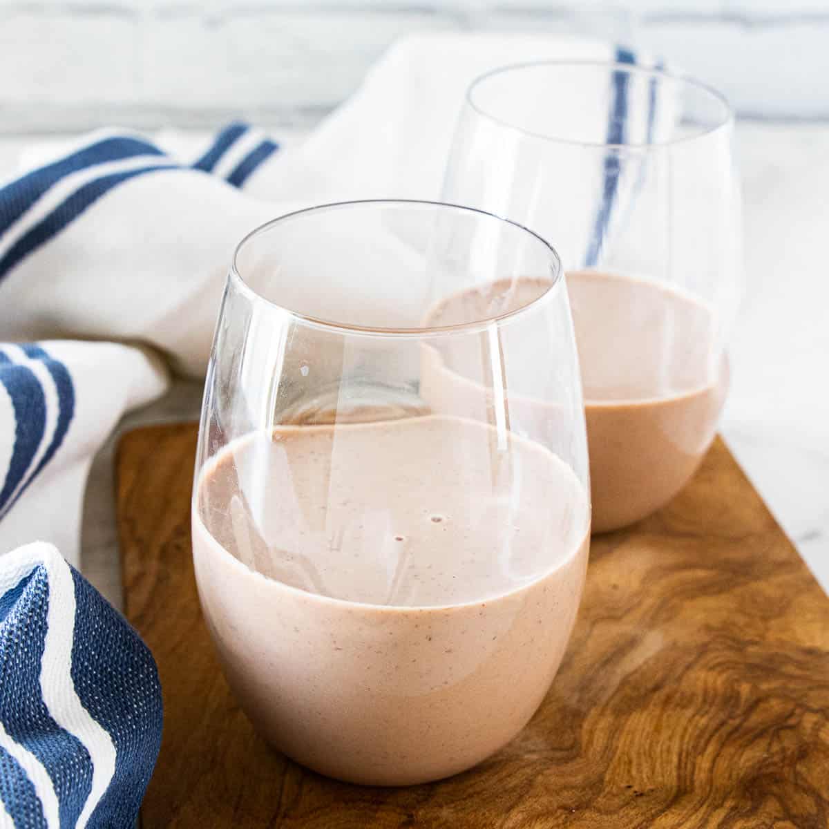 Two drinking glasses filled with a kids protein shake. 