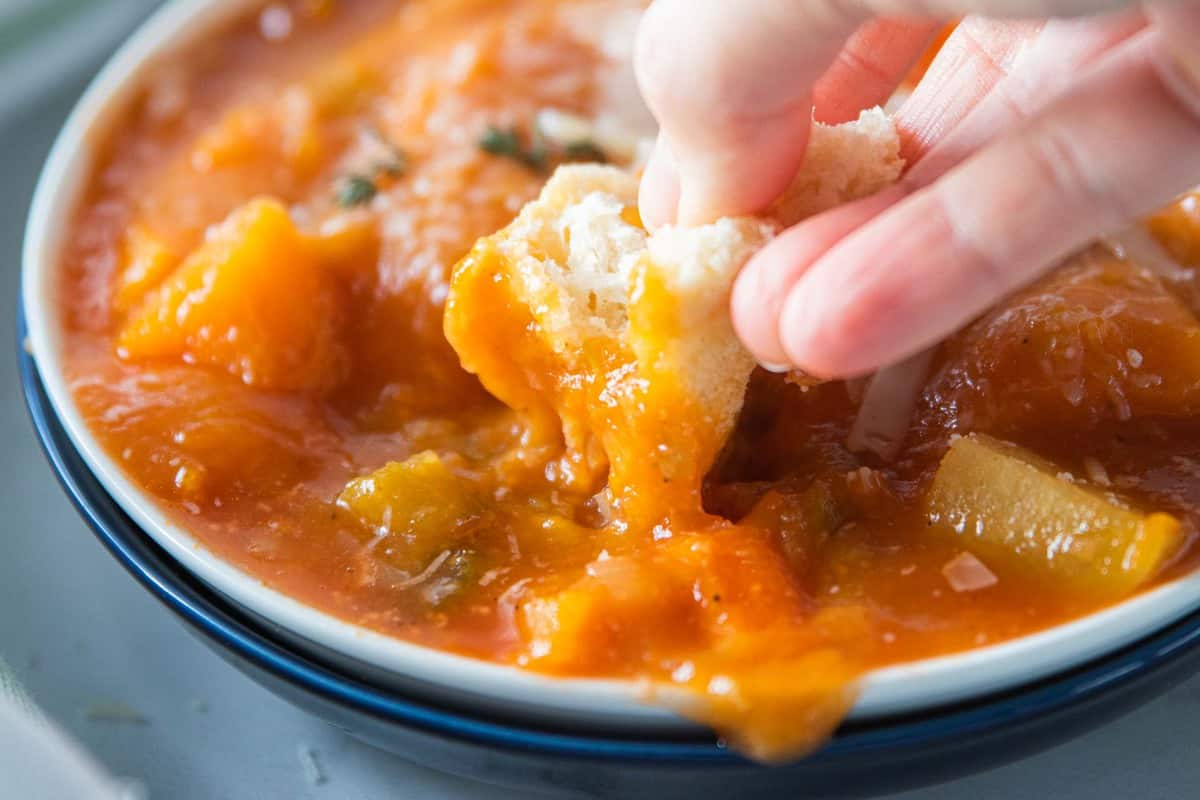 A piece of bread being dipped into soup.