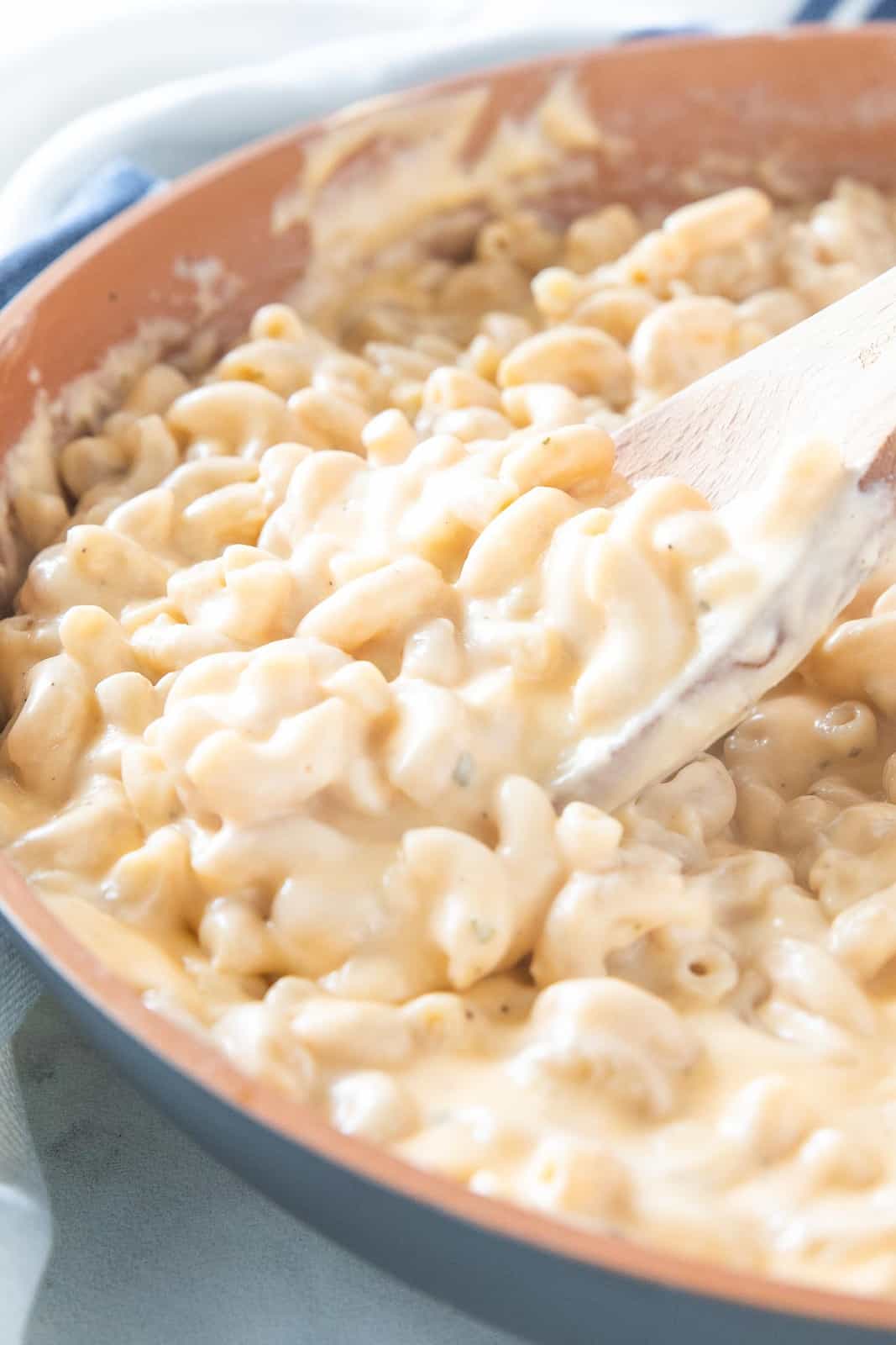 Mac and cheese being stirred in a saucepan.