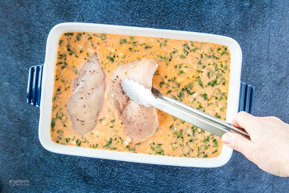 chicken breasts added to a baking dish filled with sauce