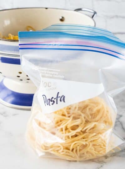 cooked pasta in a labeled ziplock bag with strainer in background
