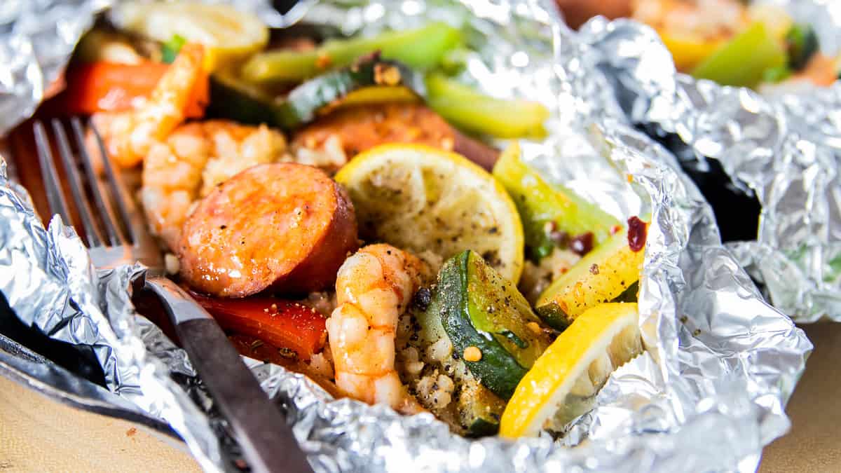 shrimp, veggies and rice in a foil pack with a fork.