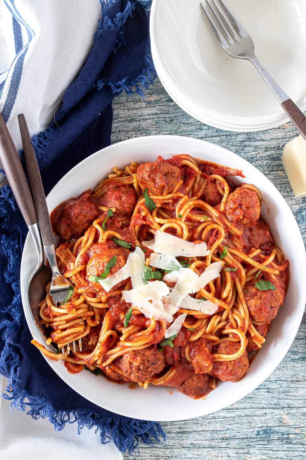 spaghetti and meatballs in a bowl with shredded parmesan on top 