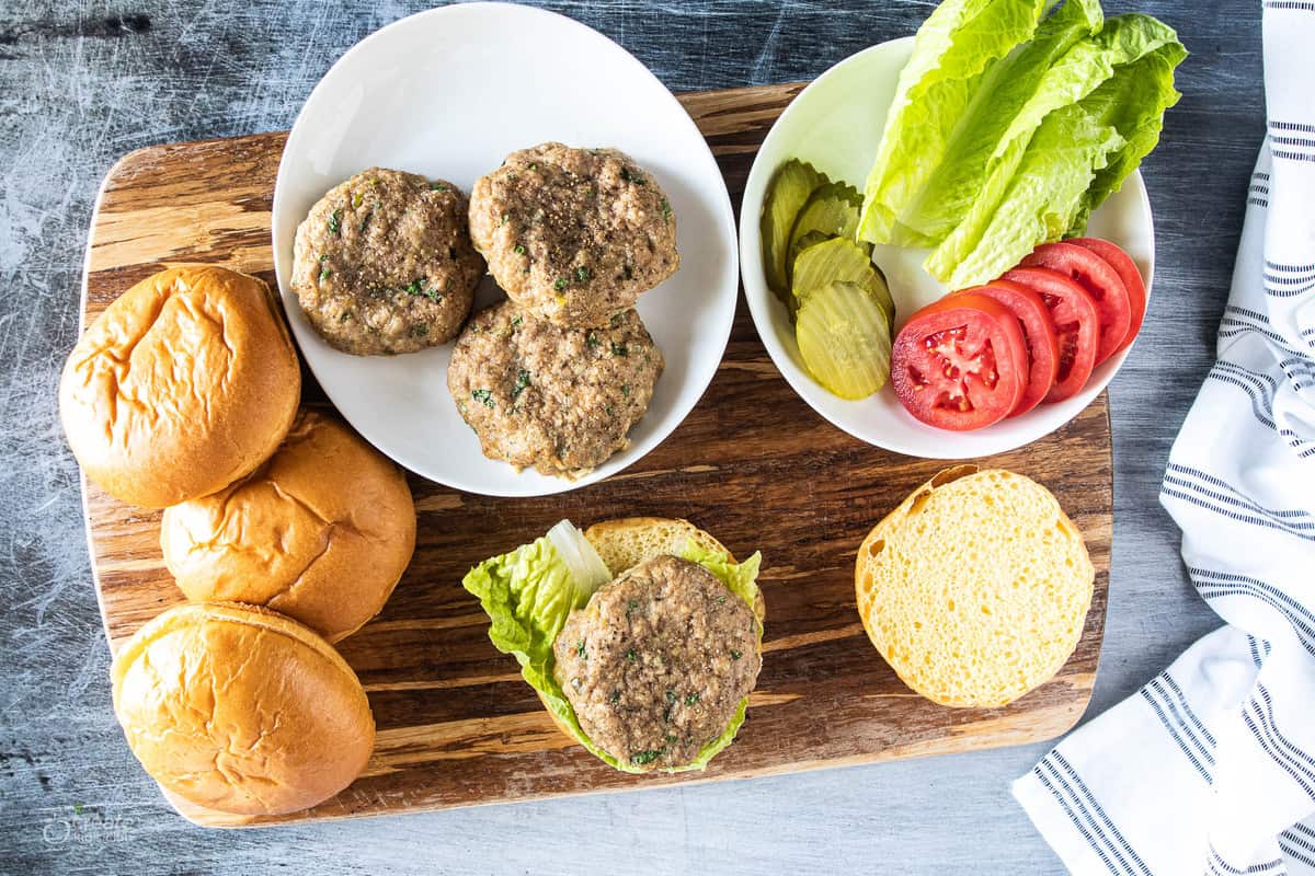 turkey burgers surrounded by buns and toppings 