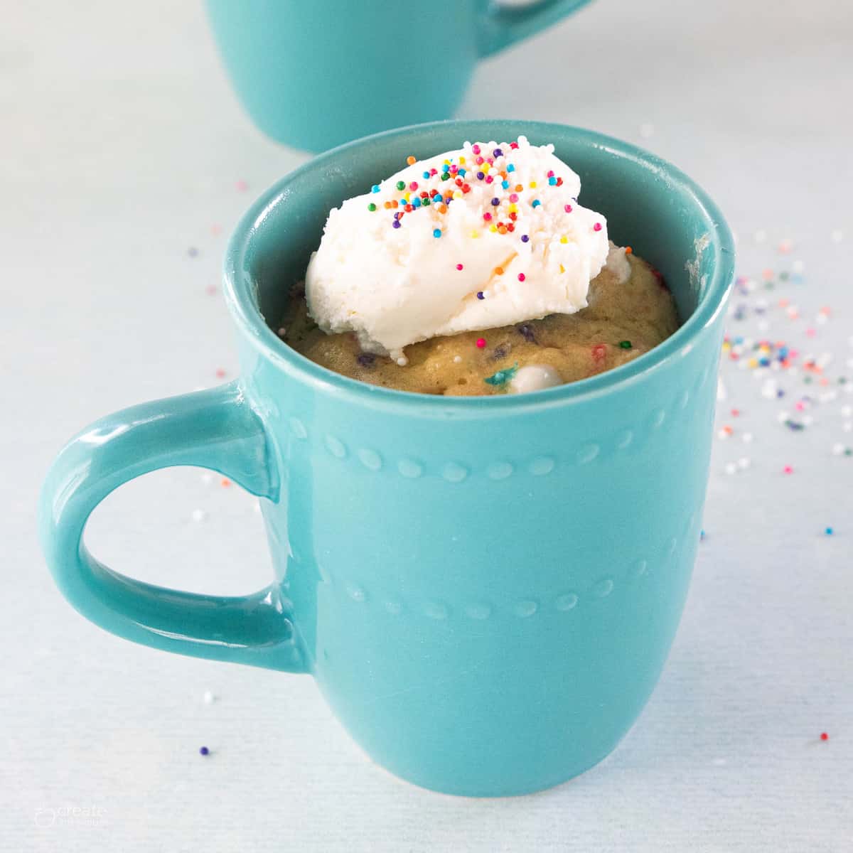 vanilla mug cake topped with ice cream and sprinkles