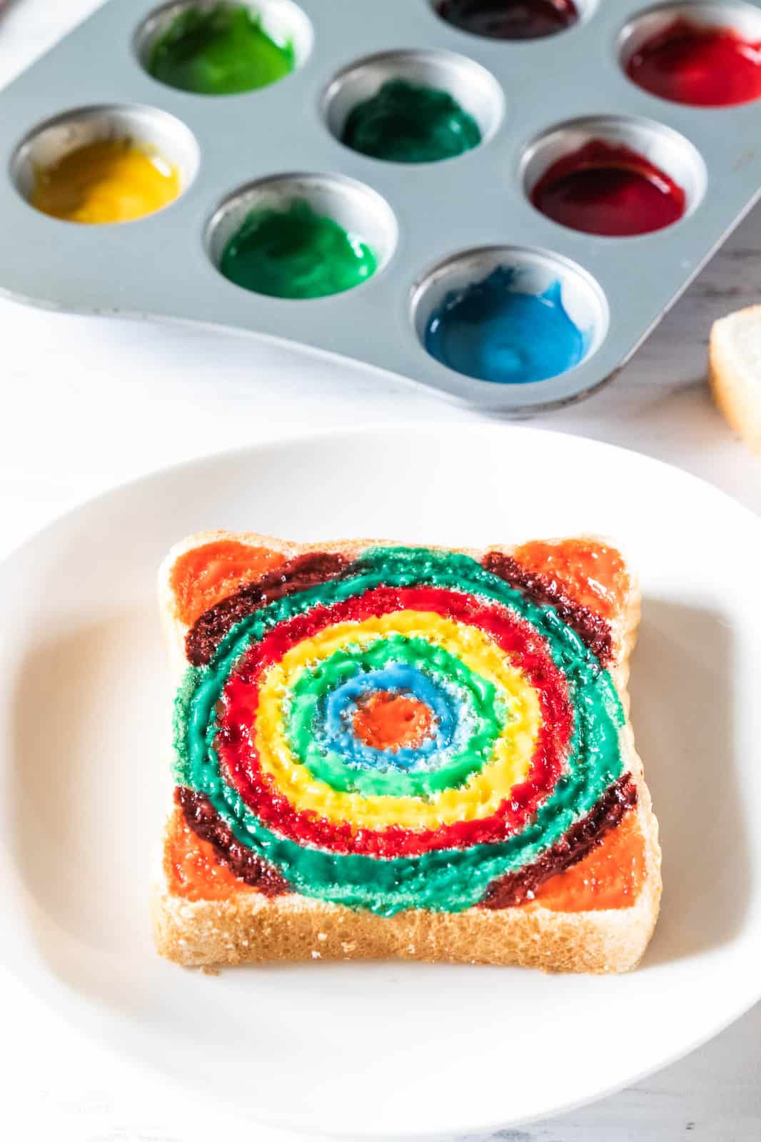 finger paint colors in a muffin tin and a painted piece of bread