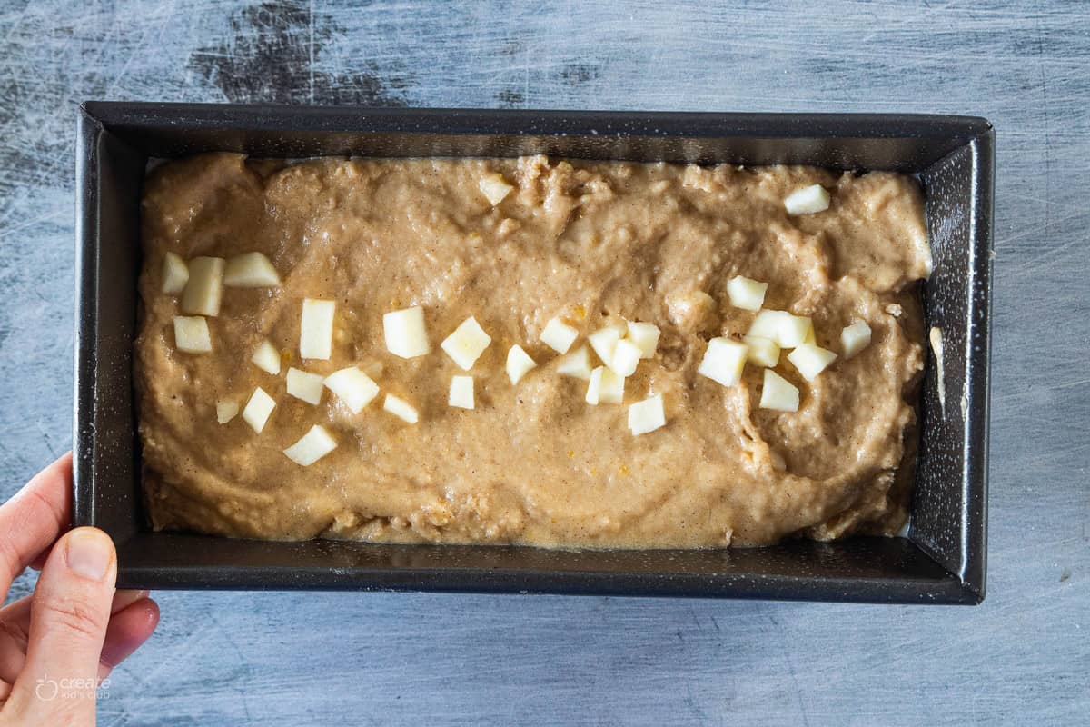 bread batter in loaf pan topped with diced apples