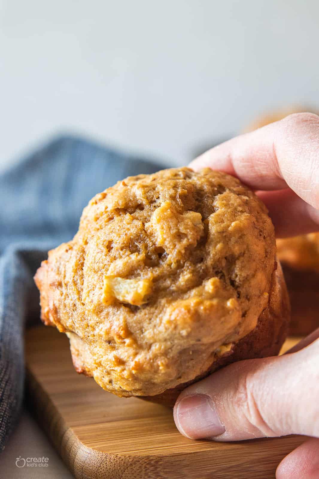 A hand holding an apple muffin. 