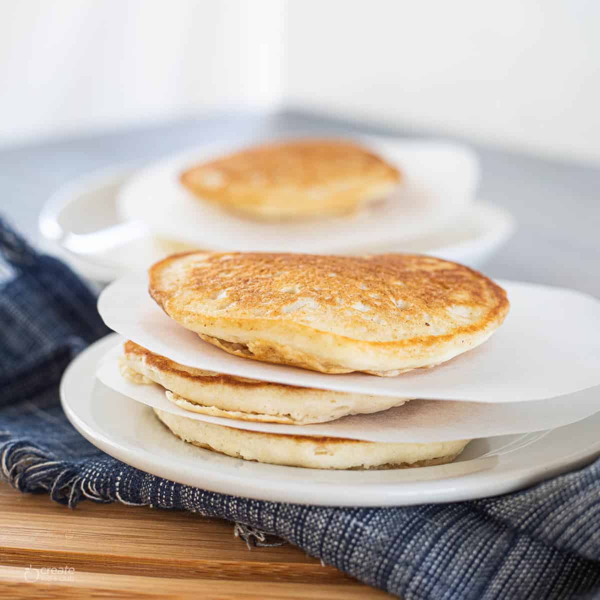 pieces of parchment paper between pancakes on a plate