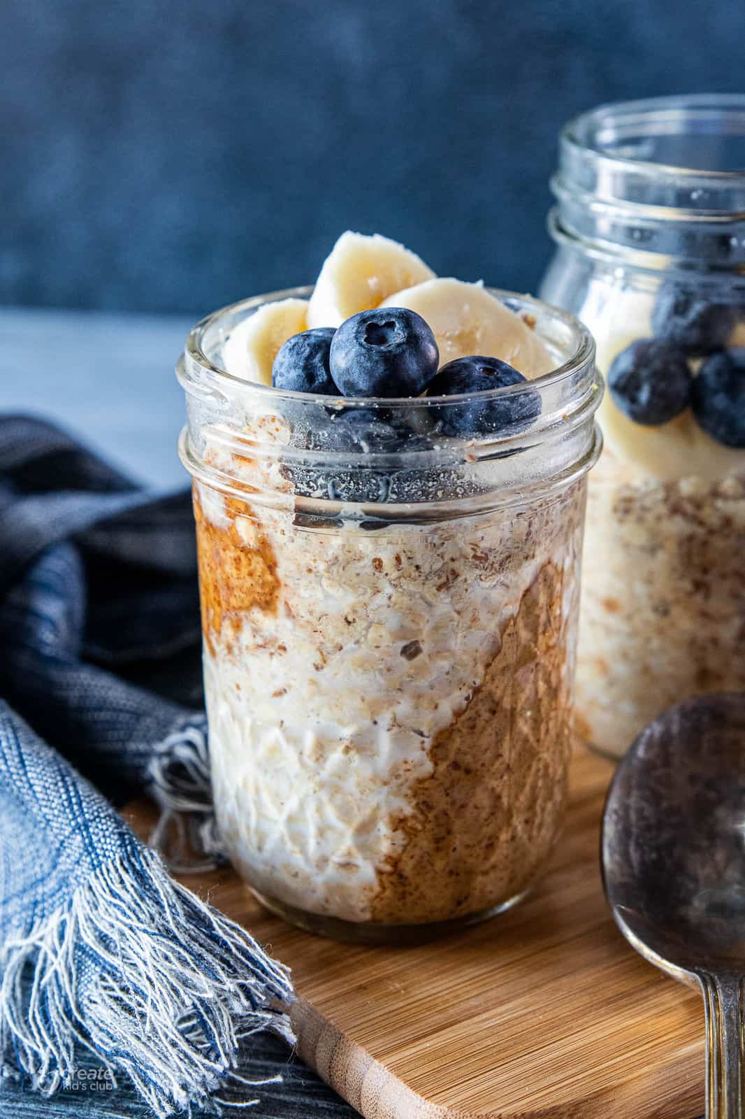 Peanut butter overnight oats in mason jars topped with fresh blueberries and banana slices