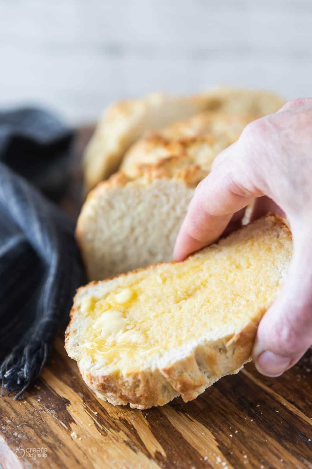 hand picking up slice of homemade bread with butter