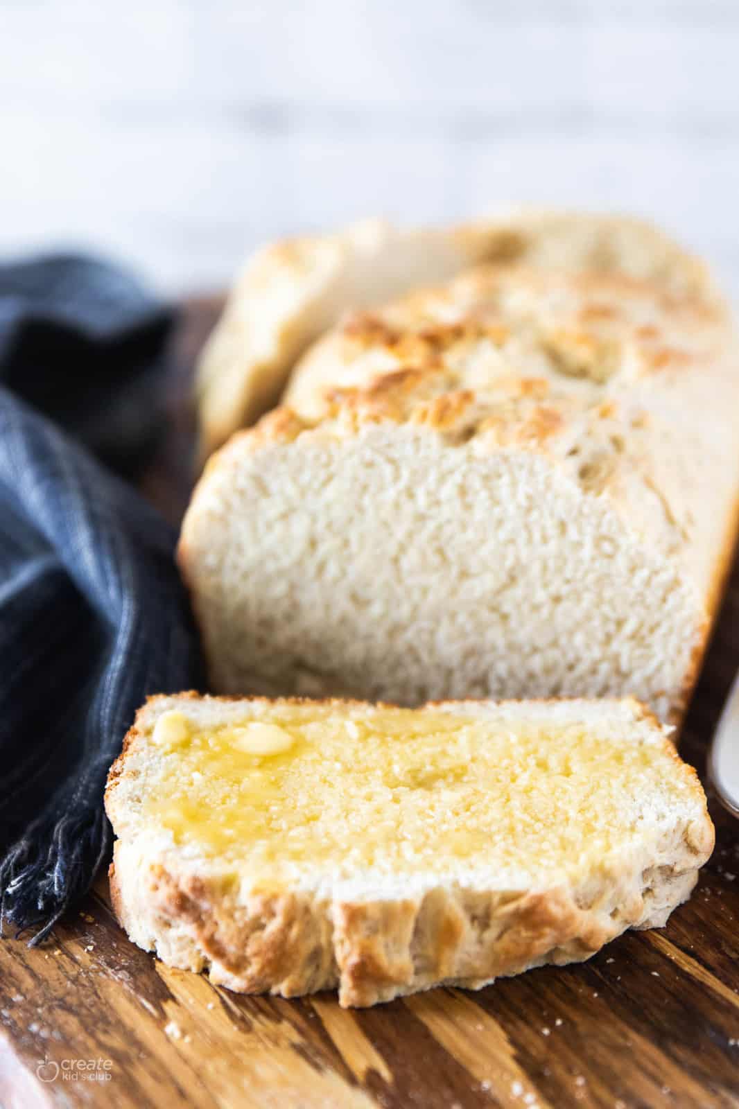 baked bread loaf with a buttered slice