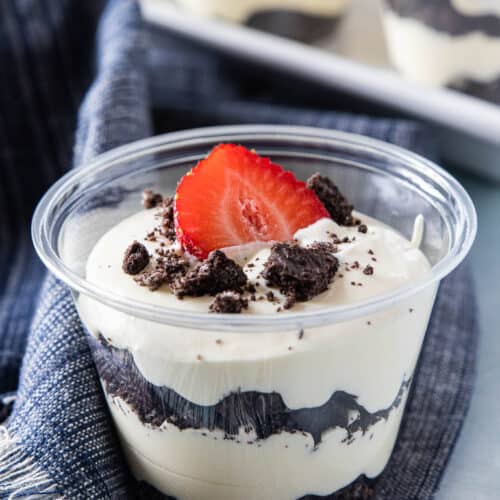 layers of crumbled oreos and pudding in cups topped with a strawberry slice