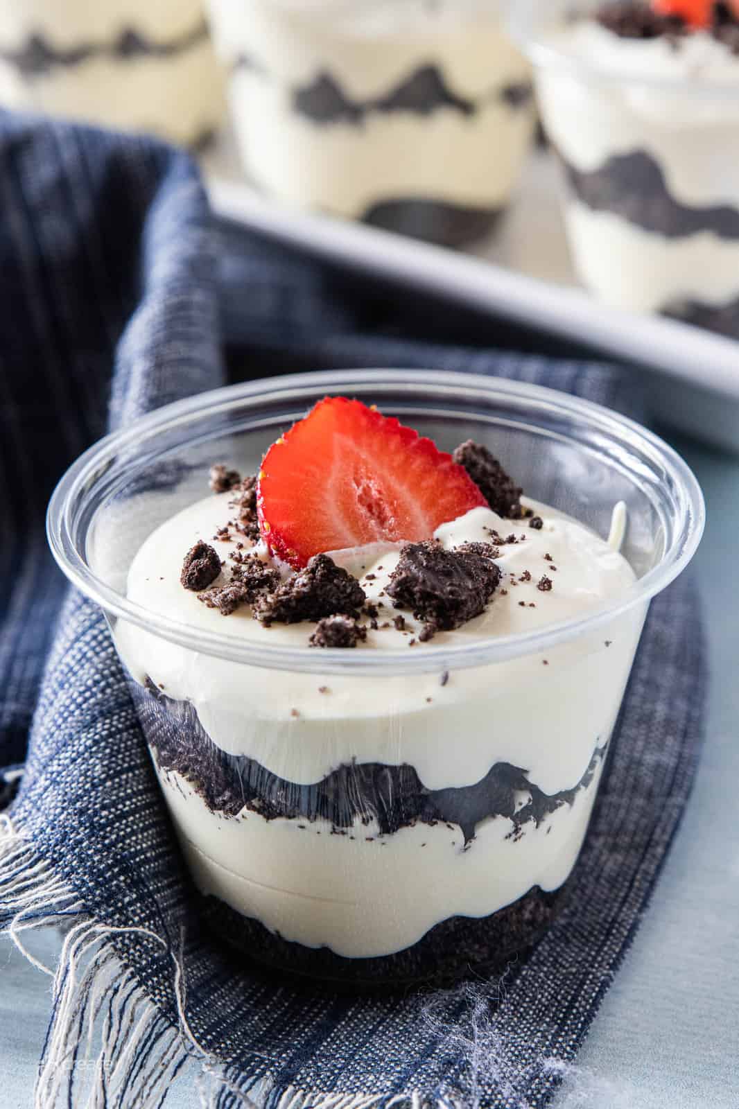 layers of crumbled oreos and pudding in cups topped with a strawberry slice