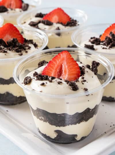 layers of crumbled oreos and pudding in cups topped with a strawberry slice