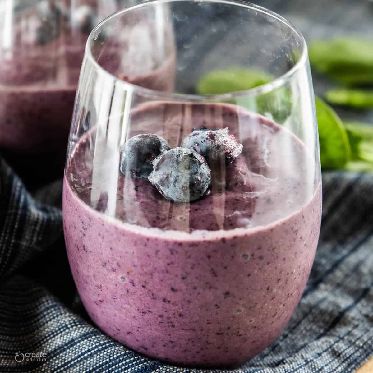 A high fiber blueberry spinach smoothie in a clear serving glass.
