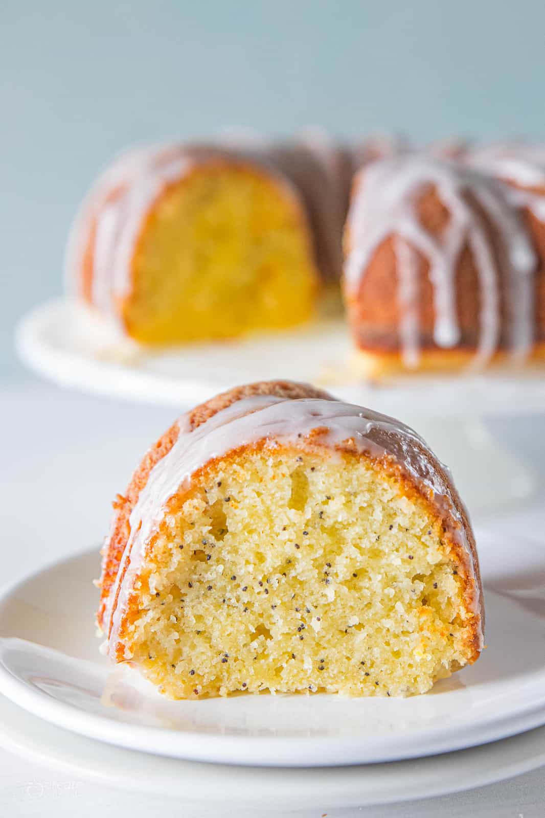 slice of lemon poppyseed cake drizzled with icing on plate