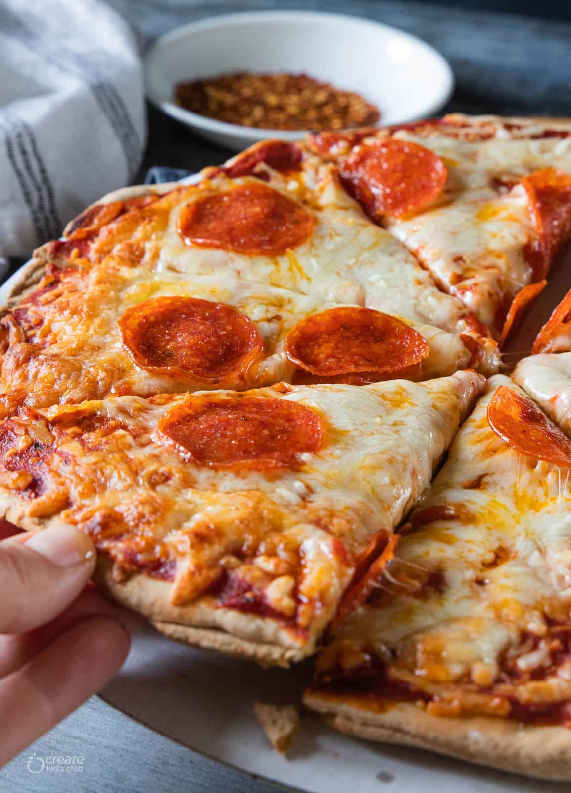 A hand is taking a slice of hot homemade pizza.