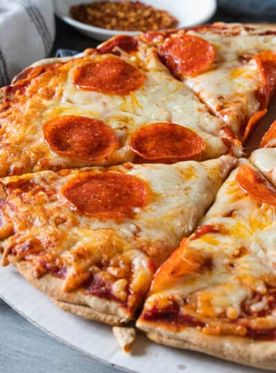 Baked homemade pizza with wheat crust shown sliced.