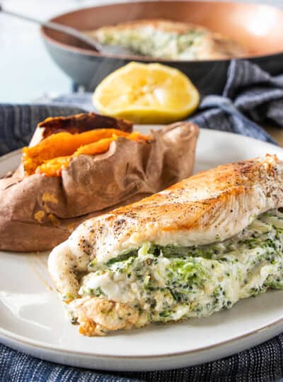 veggie and cheese stuffed chicken on plate with a sweet potato