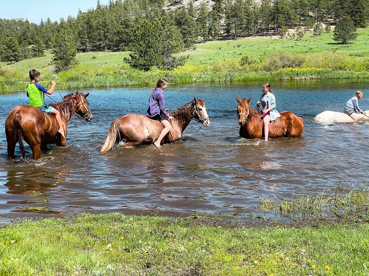 kids riding horses in water