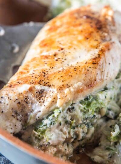 close up of broccoli and cheese stuffed chicken breast in a skillet.