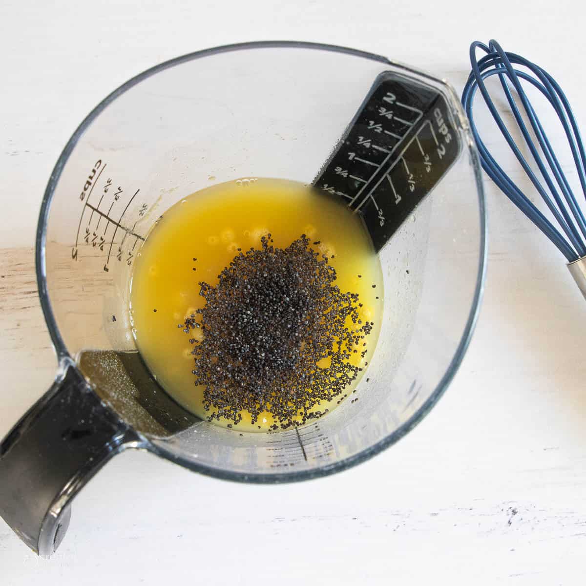 A top down shot of a pineapple juice and pudding mix dressing with poppy seeds.