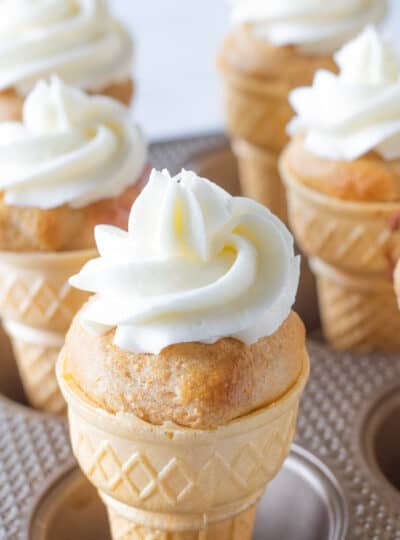 Ice cream cone cupcakes with icing shown in a muffin tin.