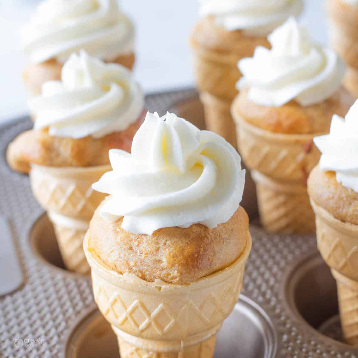 Ice cream cone cupcakes with icing shown in a muffin tin.