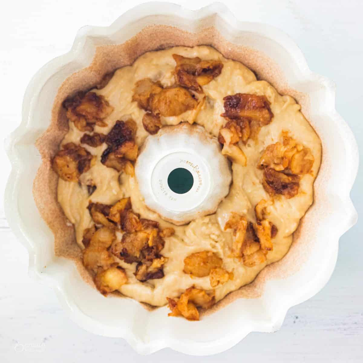 bundt pan filled with apple cake batter topped with baked apples