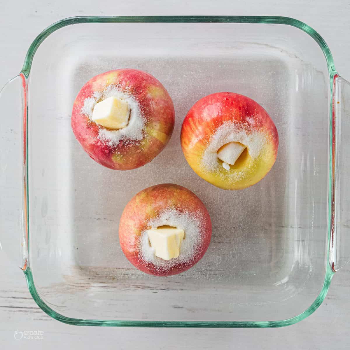 cored apples in baked dish with butter in center